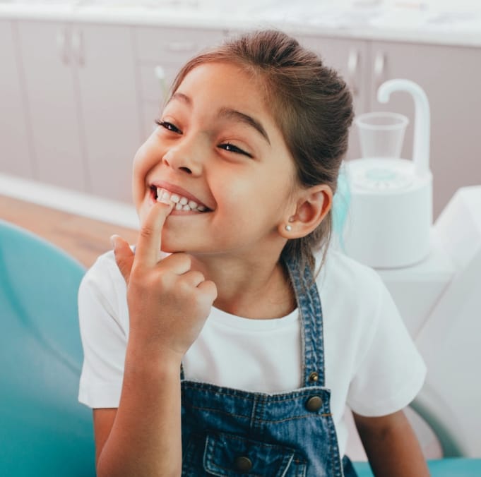 Child pointing to her smile after amalgam free dental filling